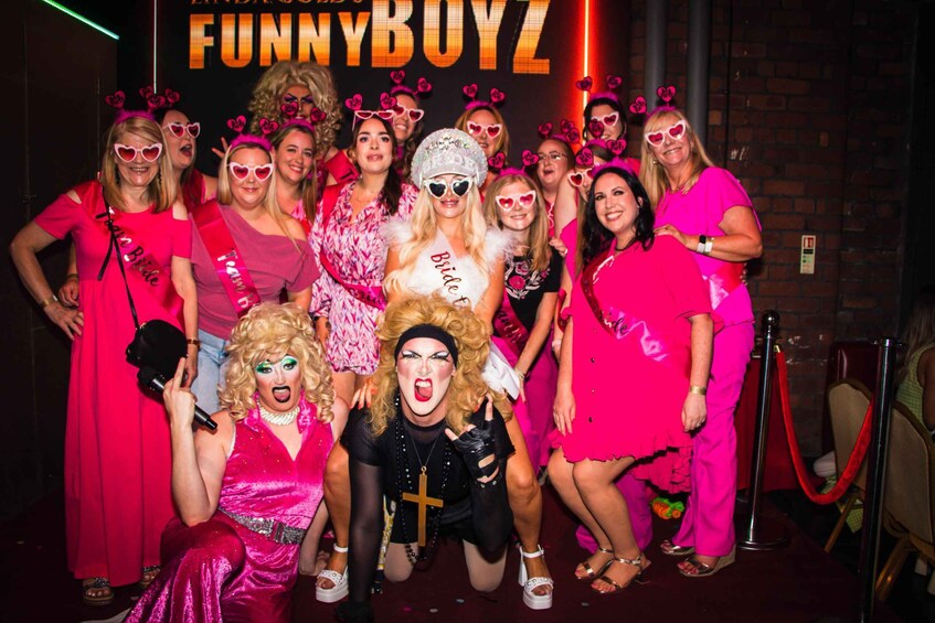 A group of people in pink and black outfits posing for a photo with a 'FunnyBoyz' sign in the background. 4