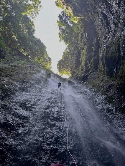A person rappelling down a rocky waterfall. 5
