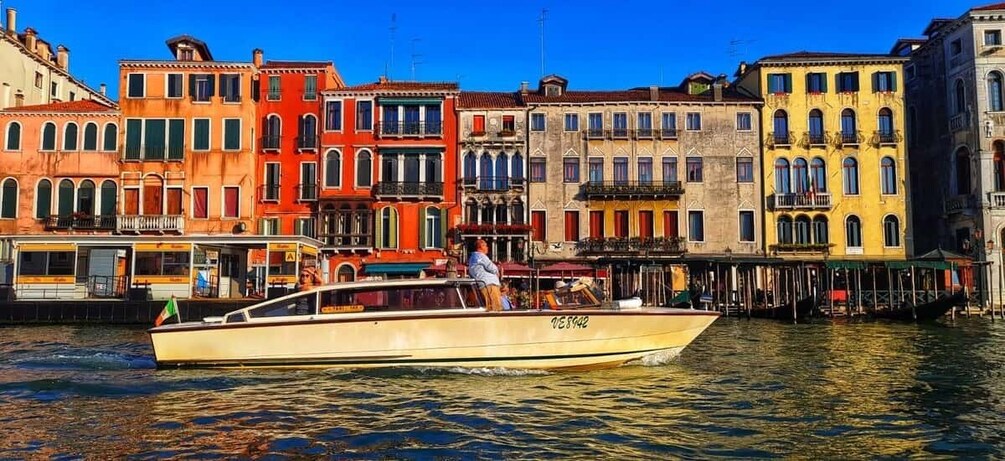 A boat on a canal with colorful buildings in the background. 1