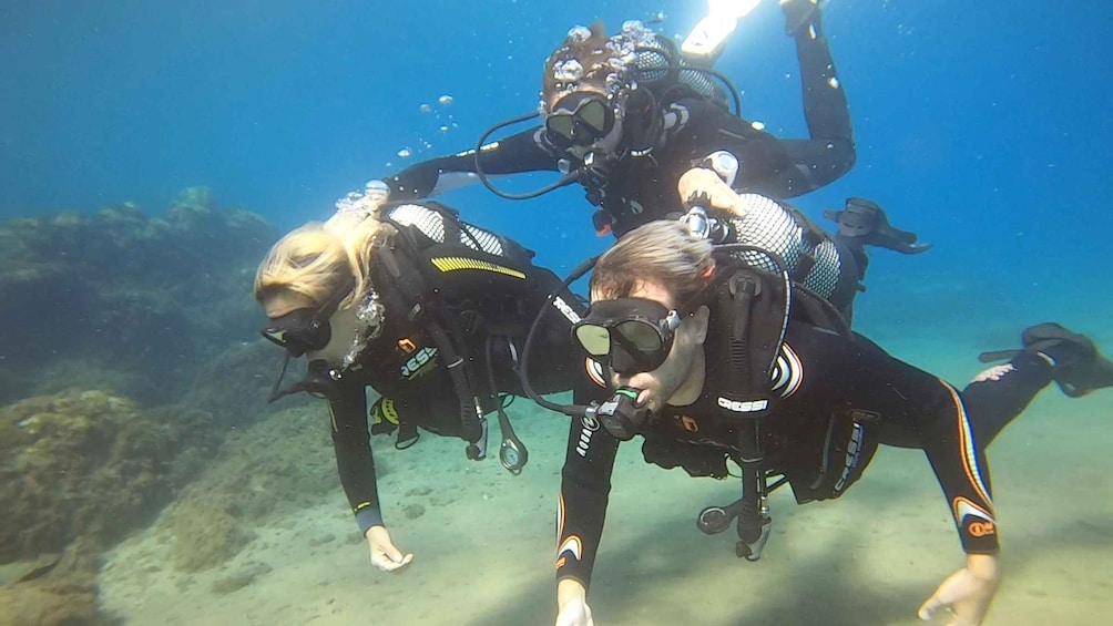 Three scuba divers underwater with fins and tanks. 1