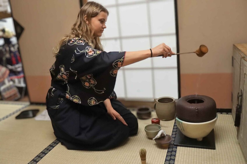 A person in traditional attire performing a tea ceremony with a whisk and a tea bowl. 4