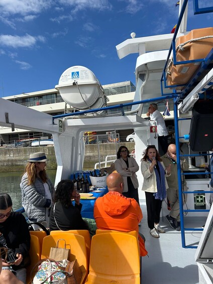 A boat with people on deck, a lifeboat, and a water body in the background. 2