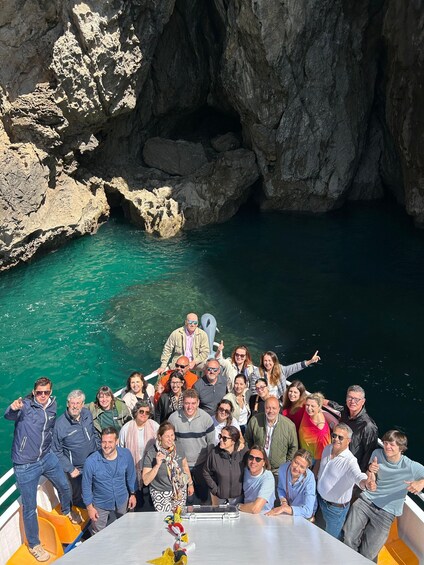 A group of people on a boat near a rocky coastline with clear blue water. 4