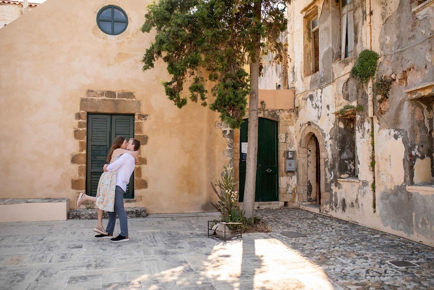 A couple embracing in a narrow street with old buildings and a tree. 2