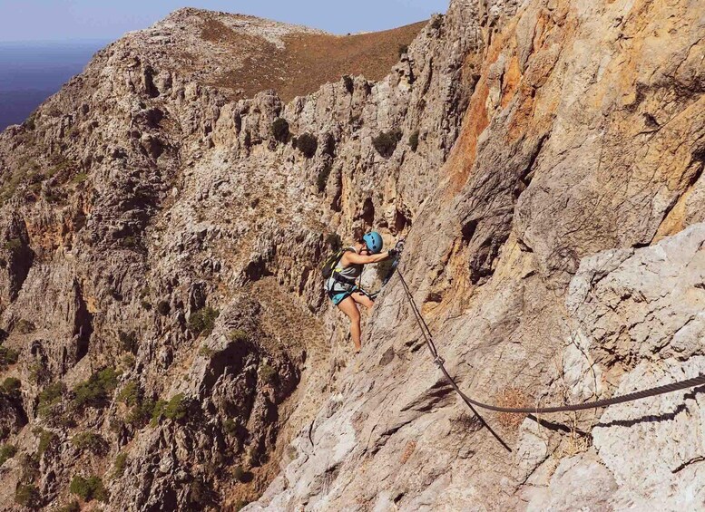 A person rock climbing a steep, rocky cliff. 1