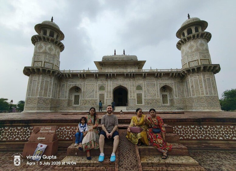 A group of people sitting on steps in front of a large, ornate building with two towers and intricate patterns. 5