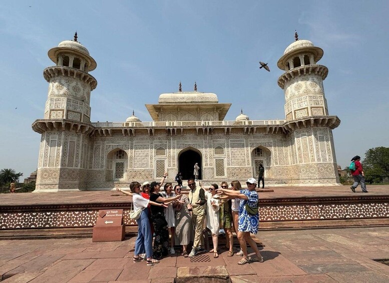 A group of people posing in front of a large, intricately designed building with domes and arches. 4