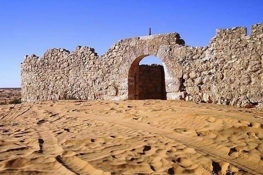 Ancient stone ruins with an arched gateway and a desert landscape. 3