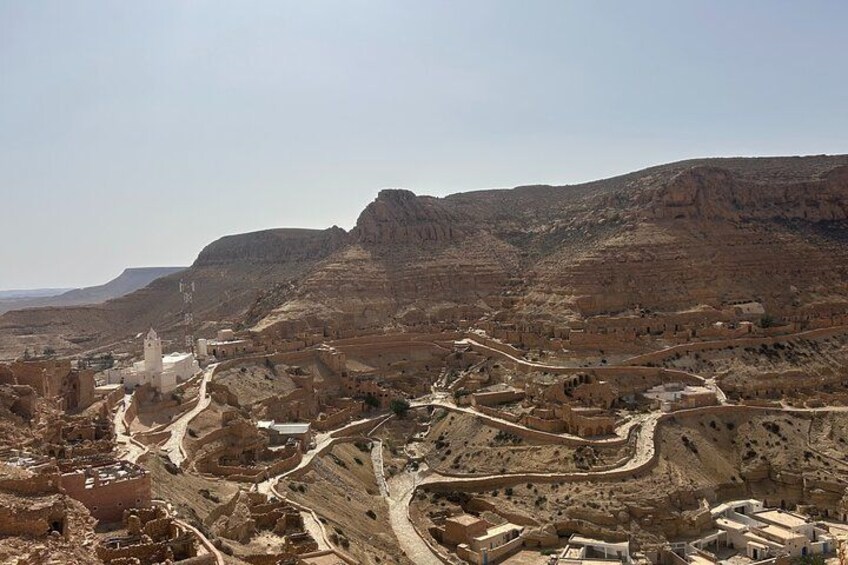 A desert landscape with ancient ruins and a prominent white church. 1