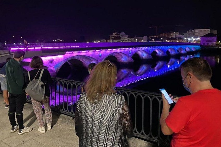 People standing by a bridge with illuminated arches. 2