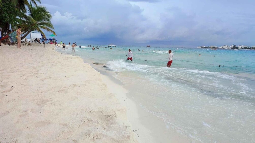 A beach with people swimming and walking along the shore. 4