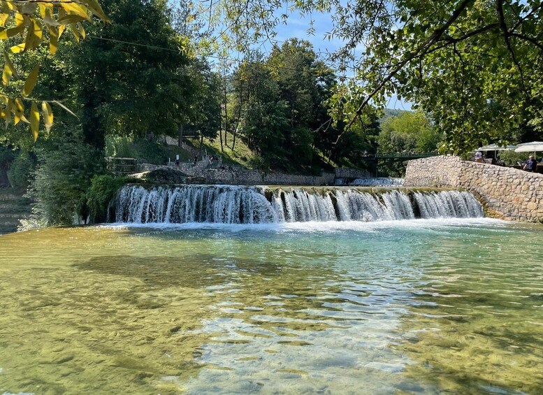 A clear water body with a waterfall and surrounding greenery. 4