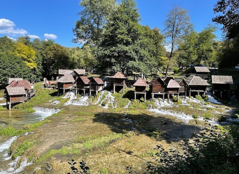 Wooden houses with thatched roofs over a flowing river. 2