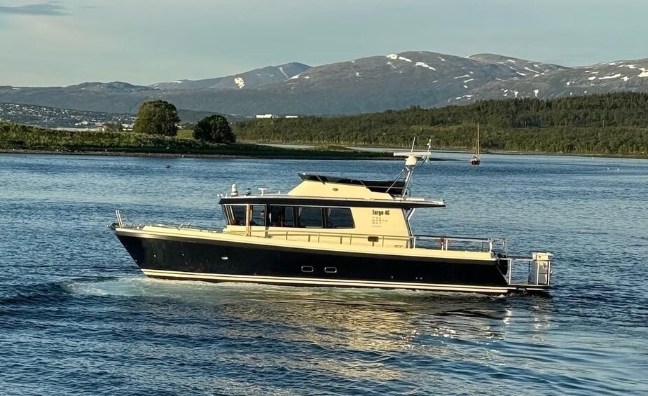 Un barco blanco y negro llamado 'Targa 46' en aguas tranquilas, con un paisaje montañoso al fondo. 2