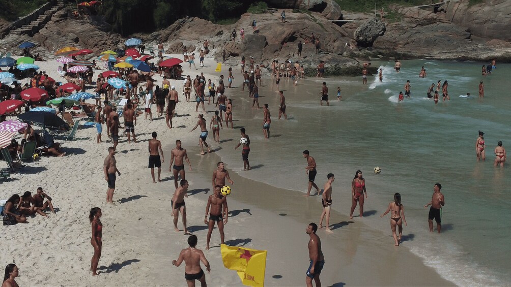 A crowded beach with people walking, playing, and sunbathing. 2