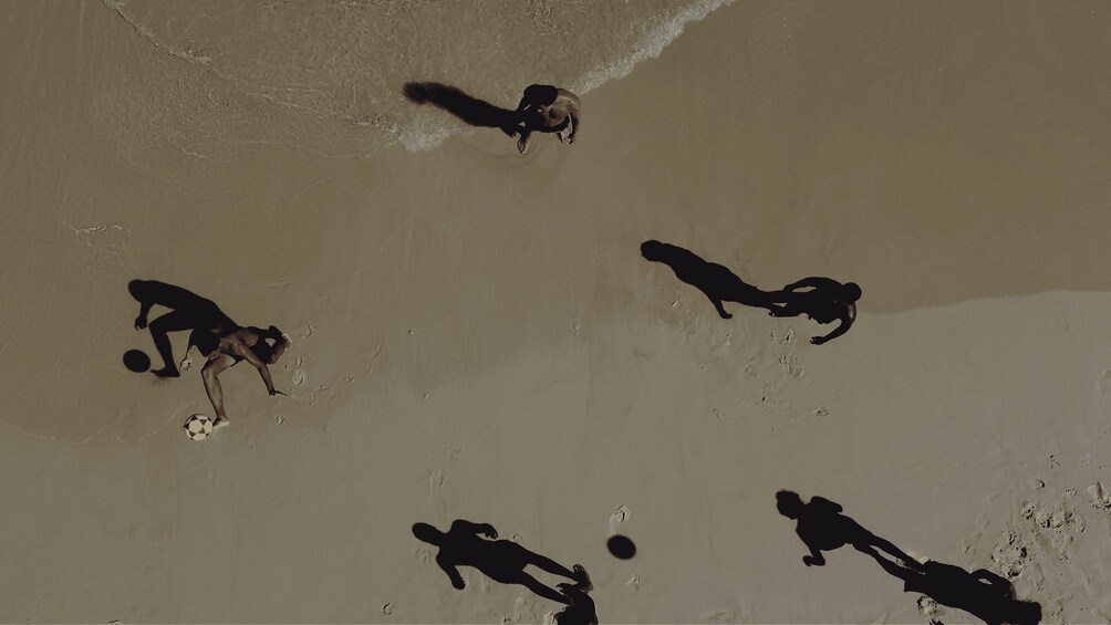 A group of people playing soccer on a sandy beach. 3