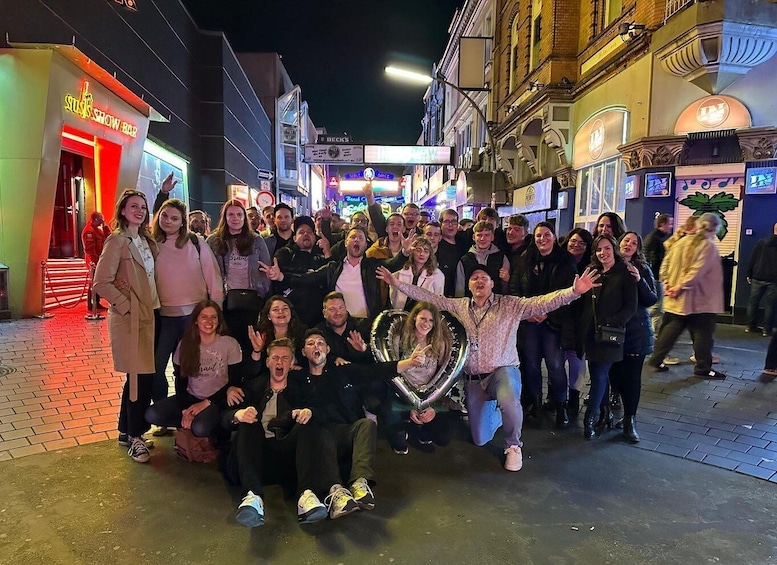 A group of people posing for a photo on a city street at night. 1