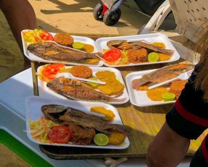 A tray with multiple servings of fried fish, tomatoes, and lime slices. 5
