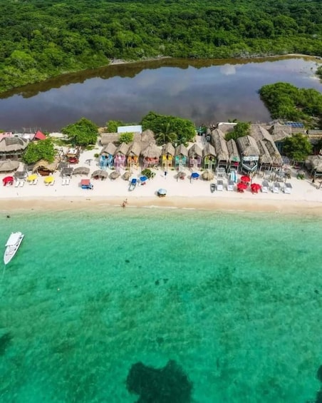 A beach with thatched-roof huts, clear turquoise water, and a boat anchored near the shore. 4