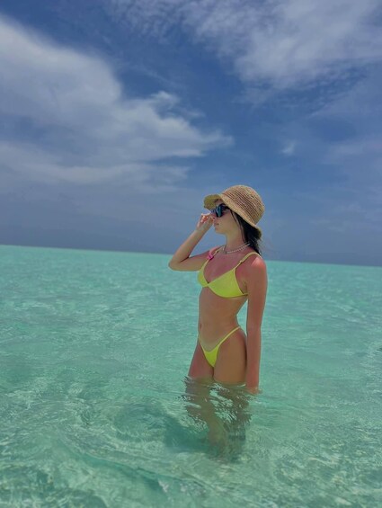 A person in a yellow bikini standing in clear turquoise water. 4