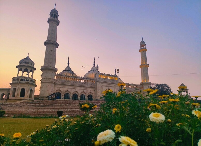 A large mosque with multiple domes and minarets, surrounded by a garden with yellow flowers. 1
