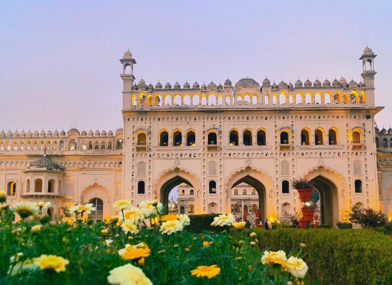 A large, ornate building with multiple arches and domes, surrounded by a garden with yellow flowers. 3