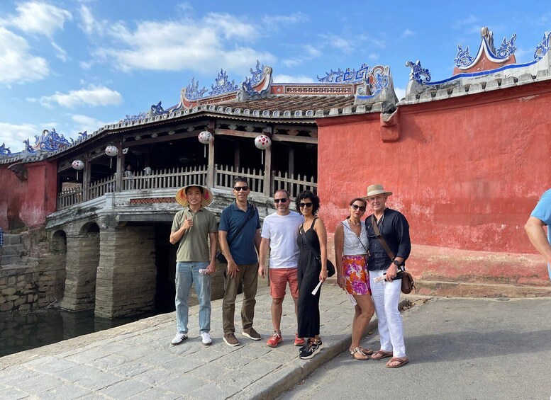 A group of people standing in front of a traditional building with ornate blue decorations and a red wall. 4