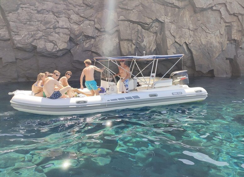 A group of people on a boat near a rocky shore. 2