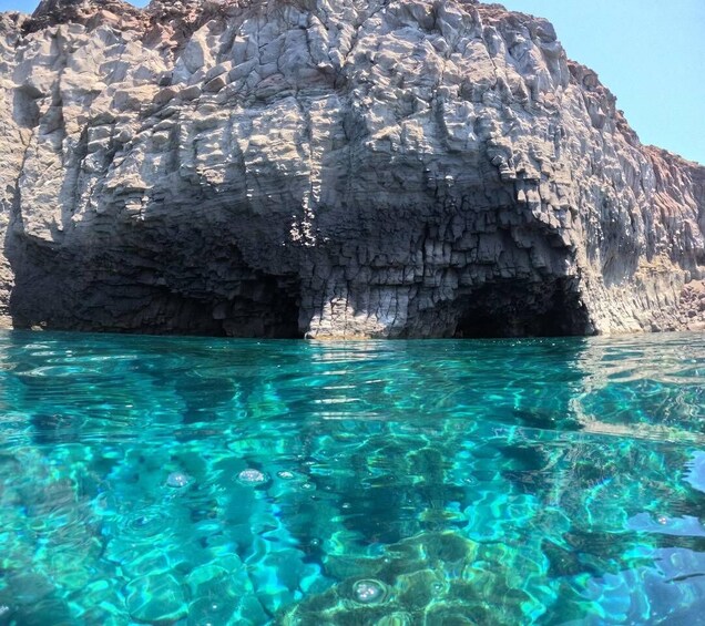 A rocky cliff with clear turquoise water in front. 5