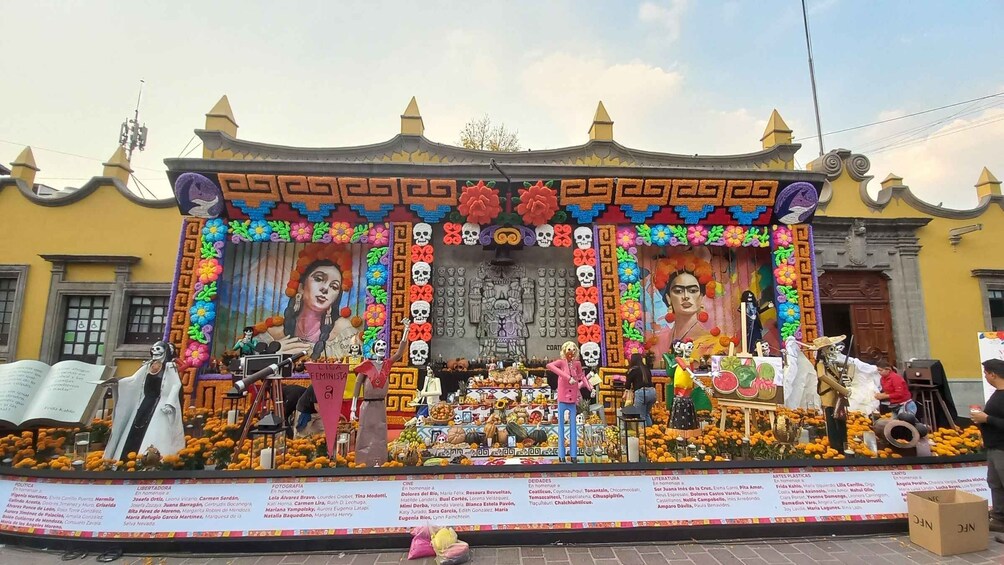 A colorful altar with skulls, flowers, and a mural. 1