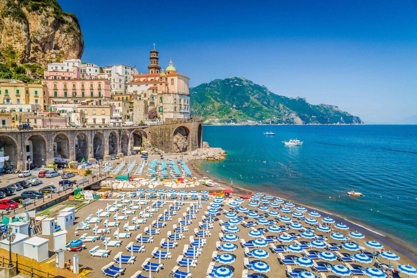 A coastal town with a beach, a historic building, and a mountain in the background. 2