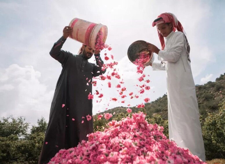 Two people pouring pink flowers into a large pile. 3