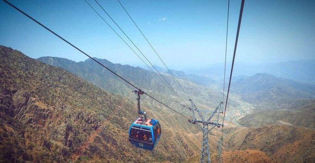 A cable car moving over a mountainous landscape. 1