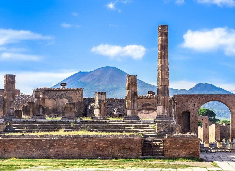 Ancient ruins with columns and an archway, set against a mountain backdrop. 3