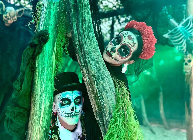 Two individuals with face paint and a skeleton in the background. 4