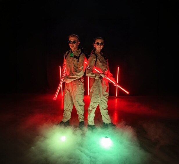 Two people in tactical gear holding red lightsabers in a dark environment with red and green lighting effects. 2