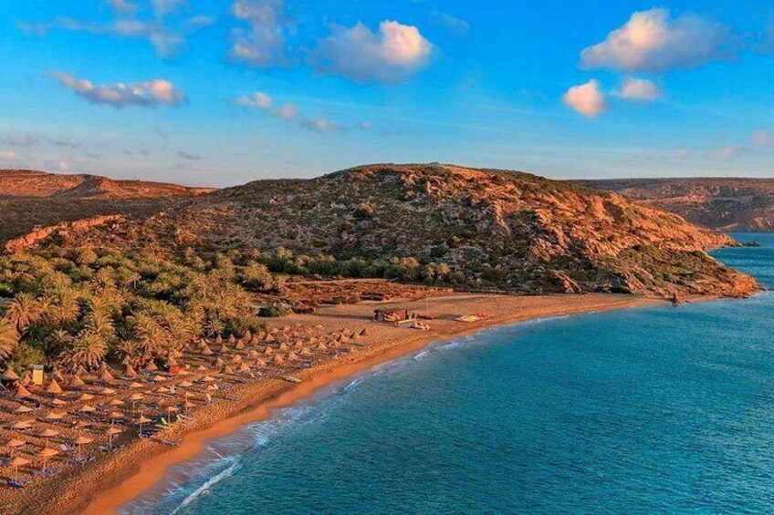 A coastal landscape with a beach, rocky hills, and sparse vegetation. 5