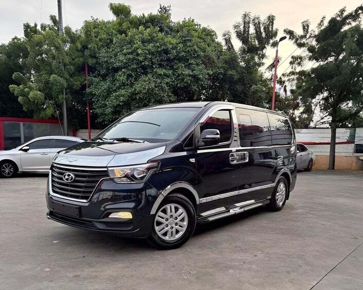 A black van parked in a lot with trees and other vehicles in the background. 5