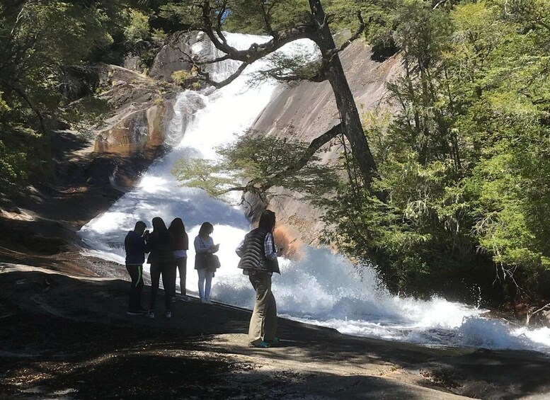 A waterfall with people standing on a path. 1