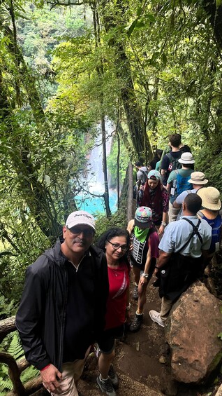 A group of hikers on a forested trail with a view of a river in the distance. 4