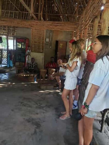 A group of people in a rustic building with a thatched roof. 2