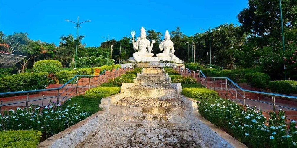 A temple complex with a central statue, surrounded by well-maintained gardens and a stone pathway leading to the statue. 2