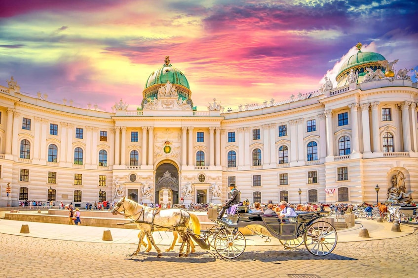 A grand building with a green dome and statues, surrounded by a cobblestone square with horse-drawn carriages. 4
