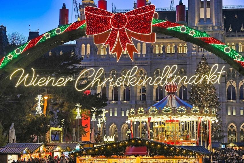 A festive market with illuminated decorations and a large bow above the entrance. 1