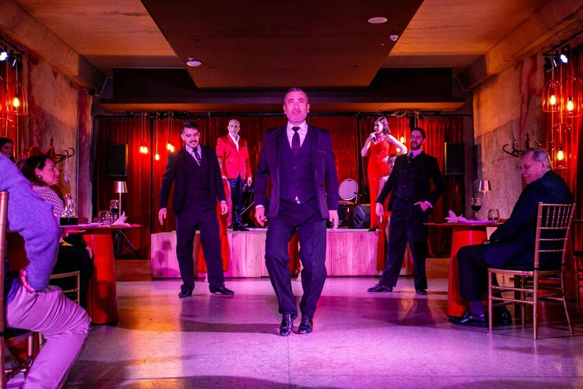 A man in a suit walking on a stage with a group of people in the background. 4