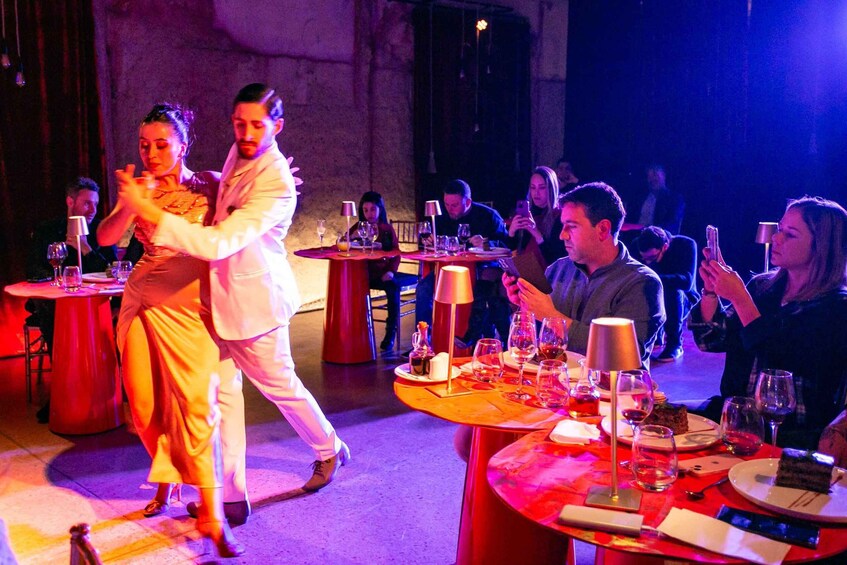 A couple dancing in a dimly lit restaurant with guests seated at tables. 3