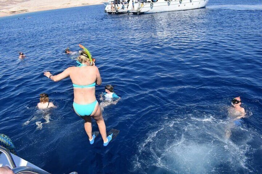 A woman in a blue swimsuit jumping into the water from a boat. 4