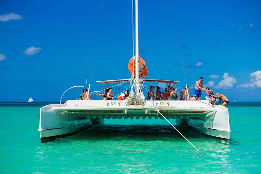 A white catamaran with people on deck, anchored in turquoise water under a clear blue sky. 3
