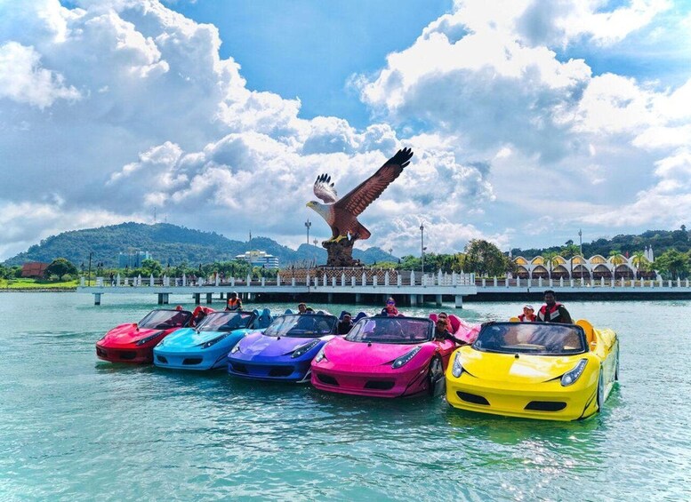 Colorful sports cars parked on water with a large eagle statue in the background. 1