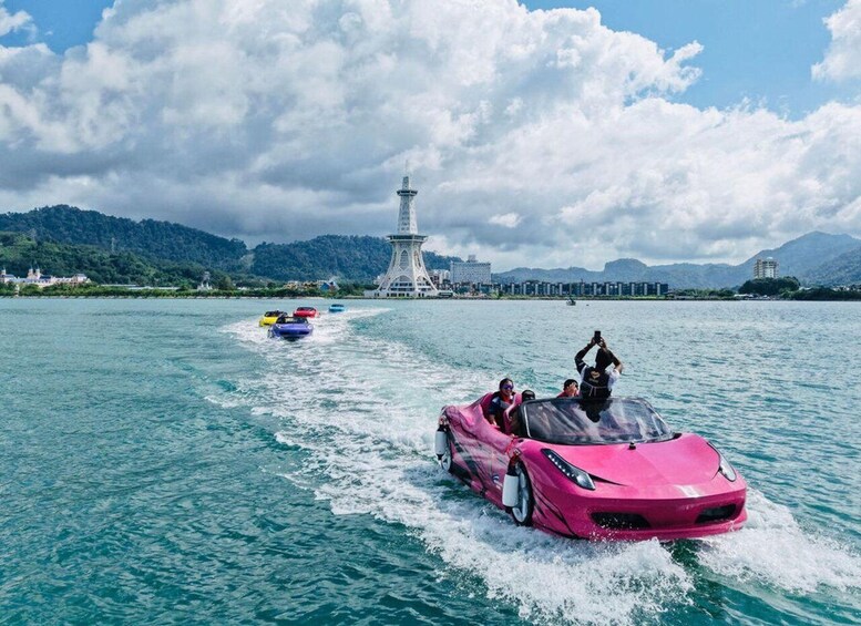 A pink sports car on water with people riding it. There are colorful boats in the background and a tower on a hill. 5